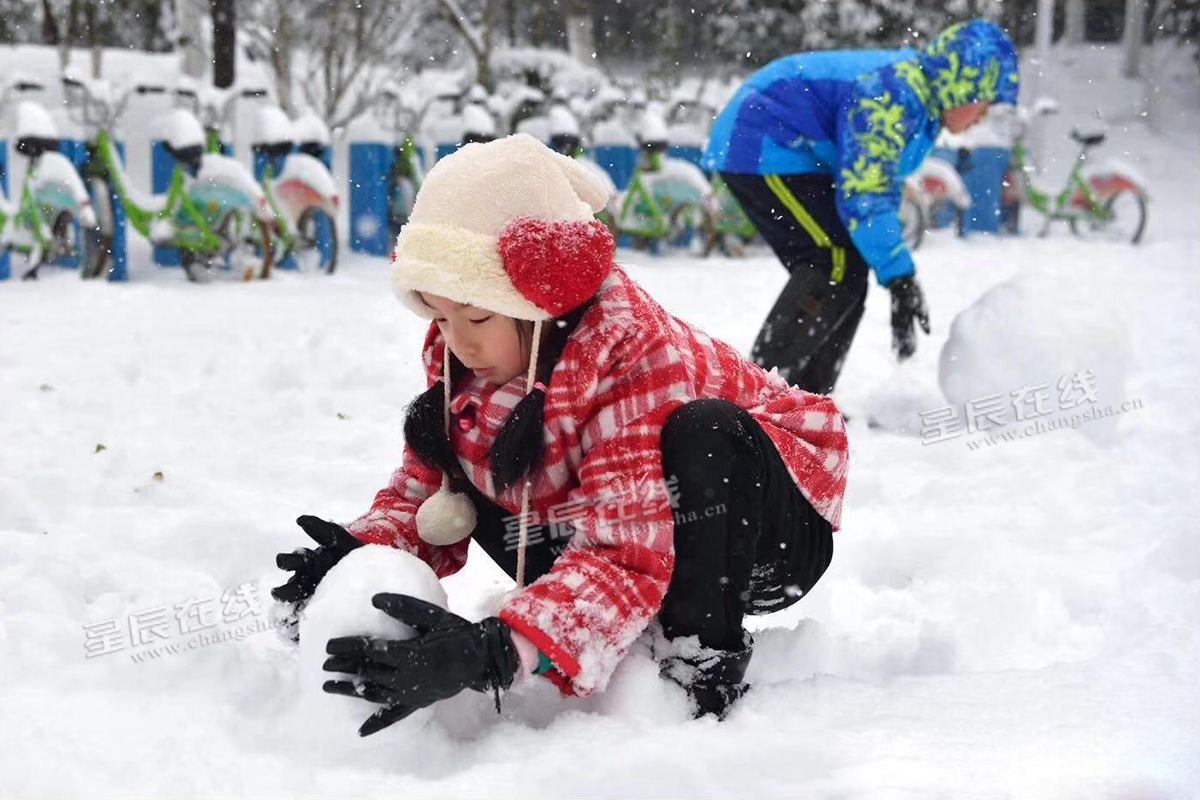 小孩愉快的在路旁堆雪人.