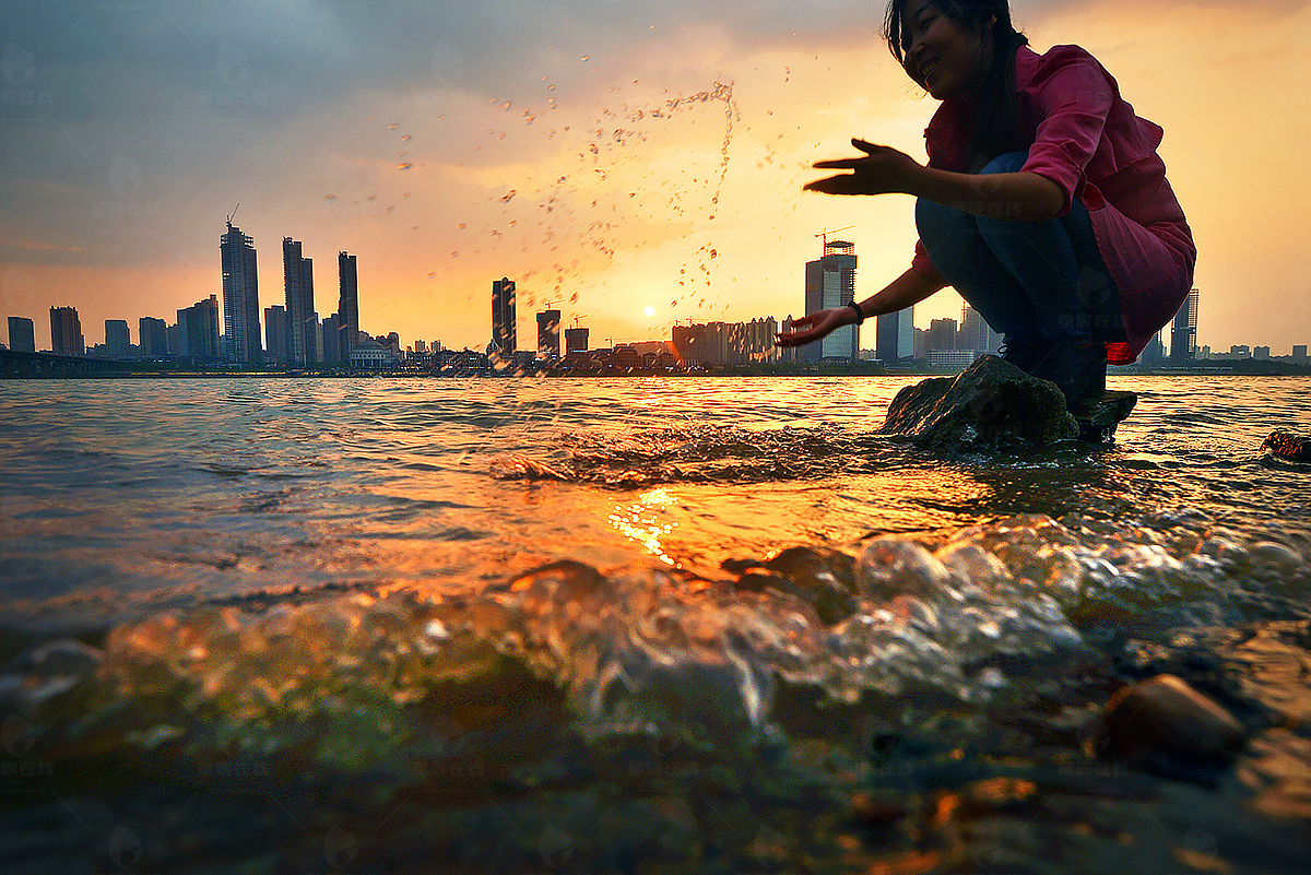 初夏的湘江边,在夕阳的映射下玩水嬉戏的女孩.